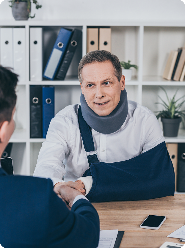Injured worker in a neck brace and arm sling shaking hands across a desk